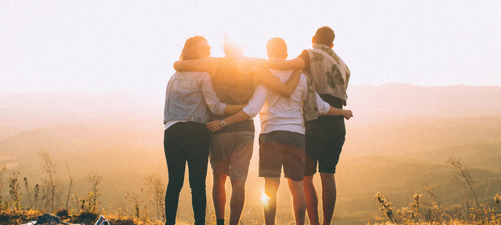 A group of young people with arms around each other, looking out over the city
